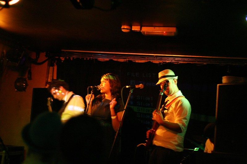 Singer and two players in an orange-lit club
