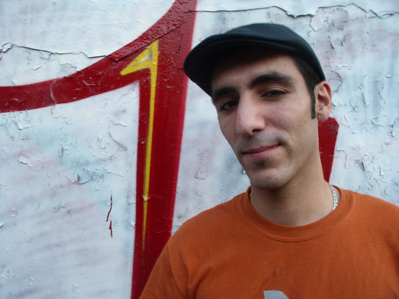 Close-up portrait in a flat cap against the IP wall