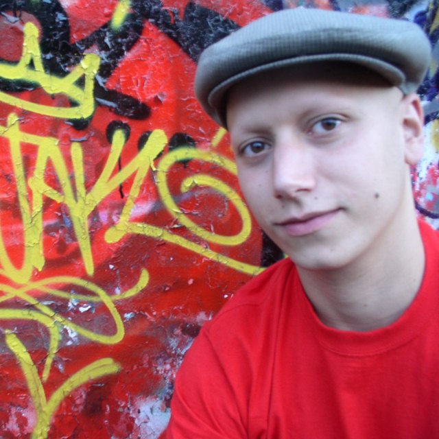 Portrait of Kojak in a flat cap in front of his yellow tag