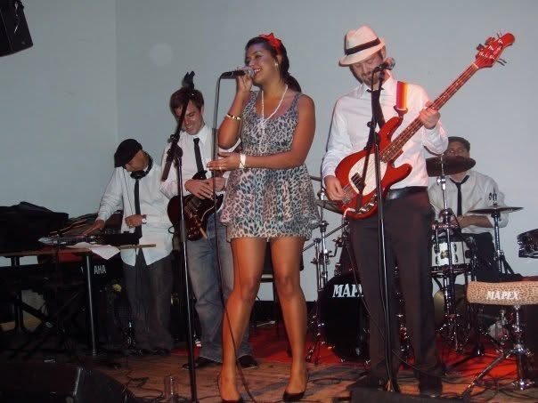 Band playing on a small stage with a drum kit